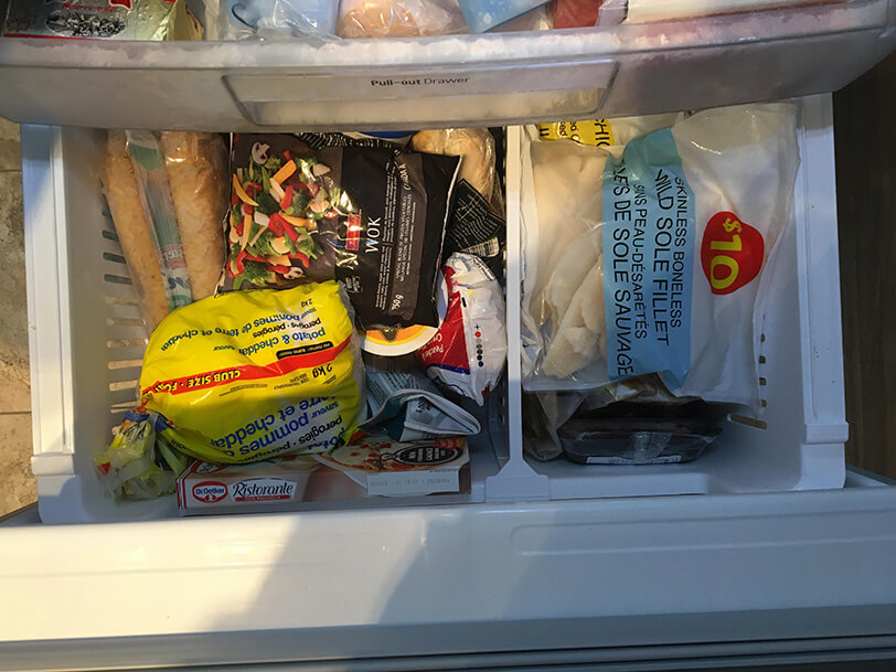 Congélateur ouvert, vue sur des légumes et du poisson