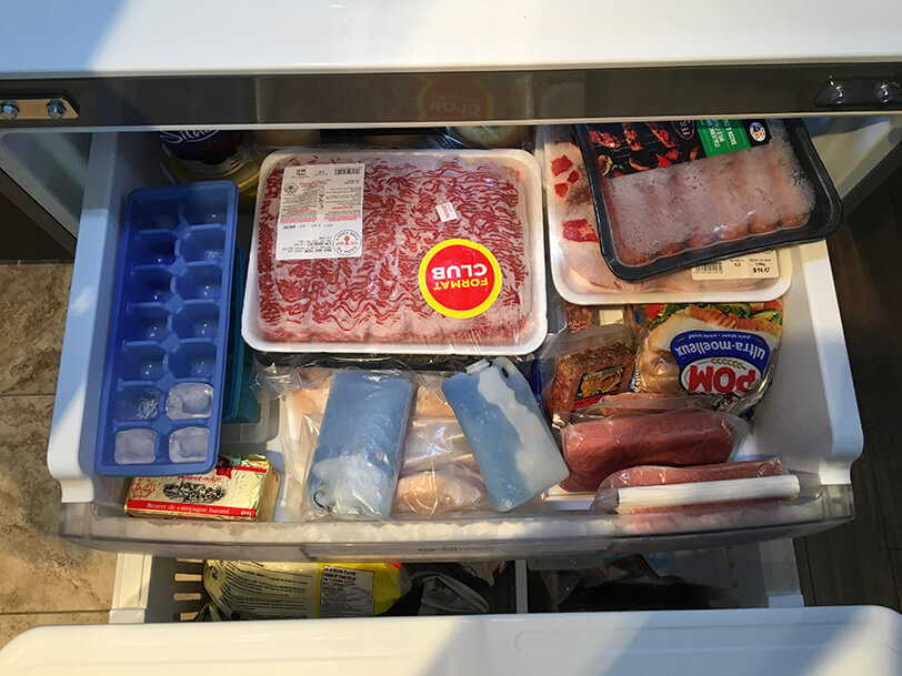 Congélateur ouvert, vue sur divers paquets de viandes