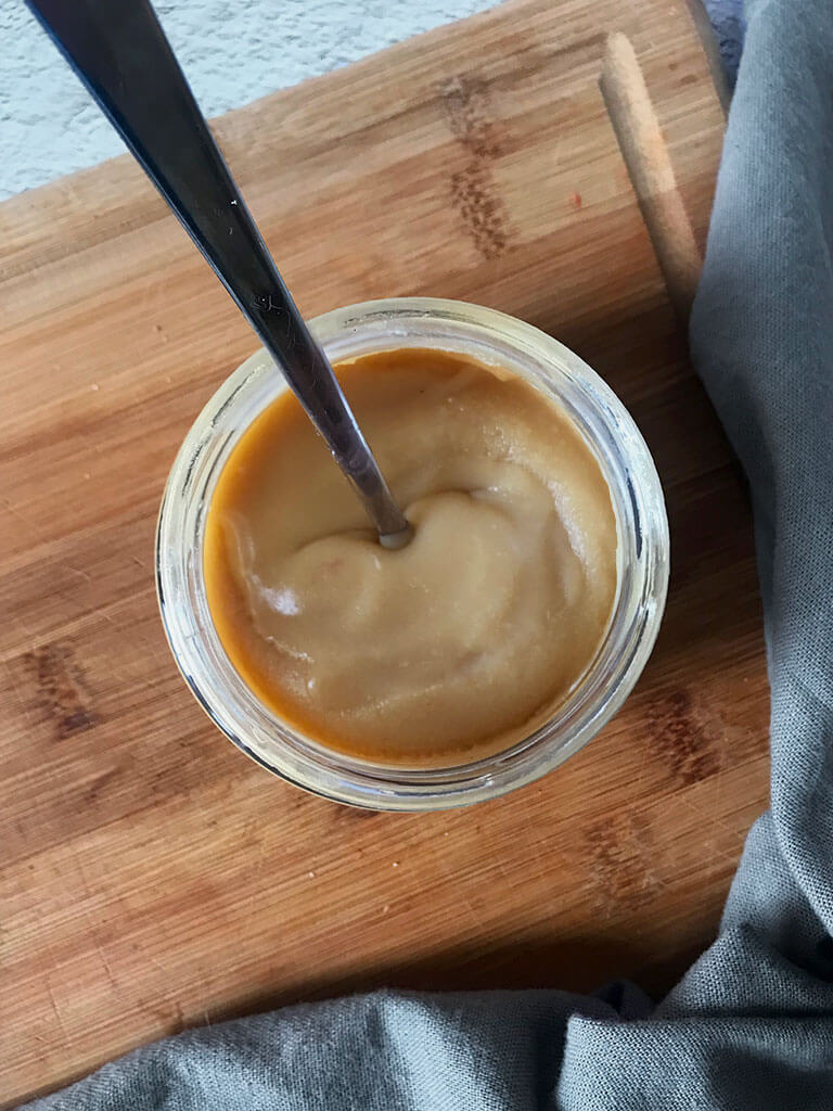 Pot de caramel maison avec la cuillère à l'intérieur