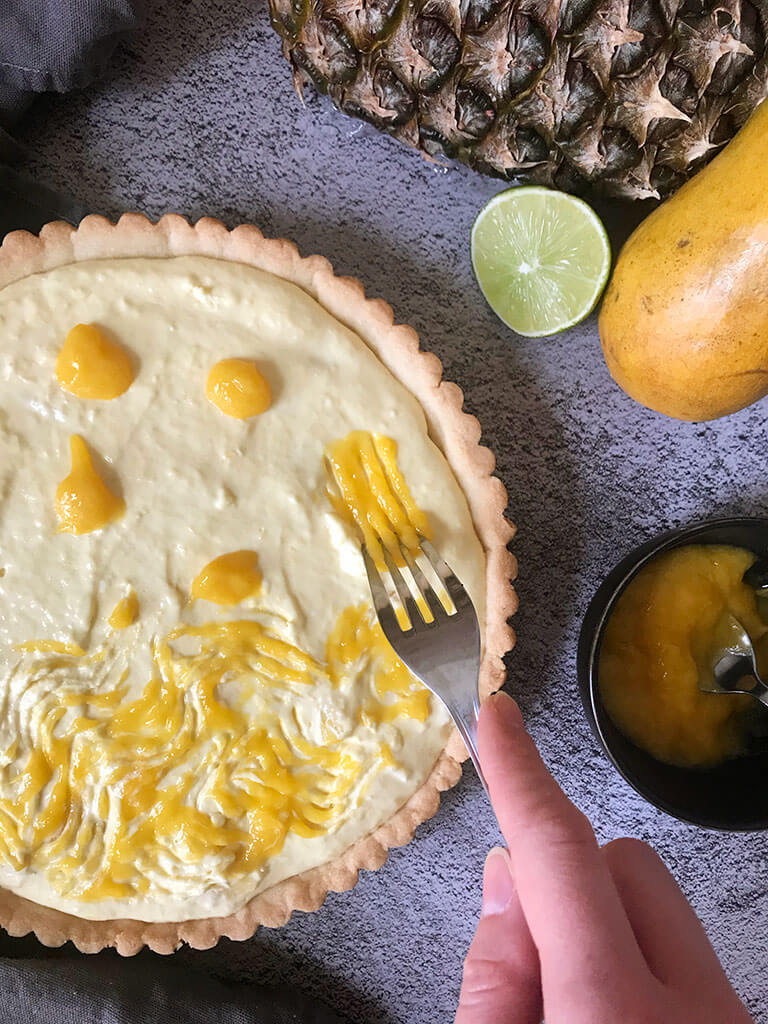 cheesecake avec fourchette pour étendre la purée de mangue